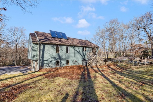 view of side of home featuring solar panels, a yard, and a deck