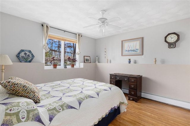 bedroom featuring light hardwood / wood-style floors, ceiling fan, and a baseboard heating unit