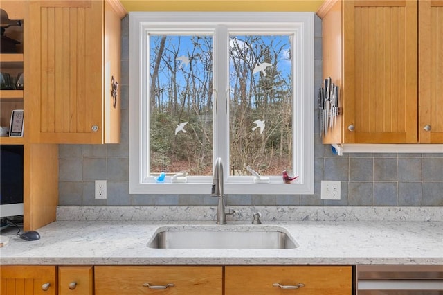 kitchen with decorative backsplash, light stone counters, plenty of natural light, and sink