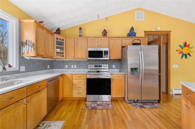 kitchen featuring light stone countertops, appliances with stainless steel finishes, tasteful backsplash, baseboard heating, and sink