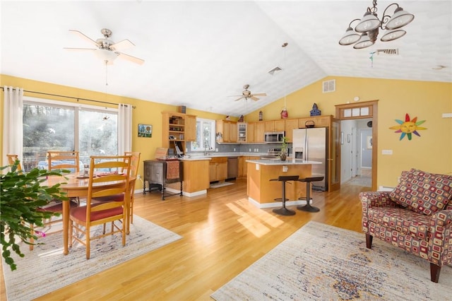 living room featuring ceiling fan with notable chandelier, light wood-type flooring, and lofted ceiling