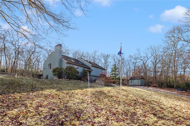 view of side of home featuring a storage shed and a lawn