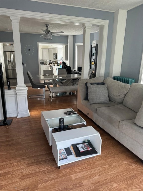 living room featuring wood-type flooring, a textured ceiling, and ceiling fan