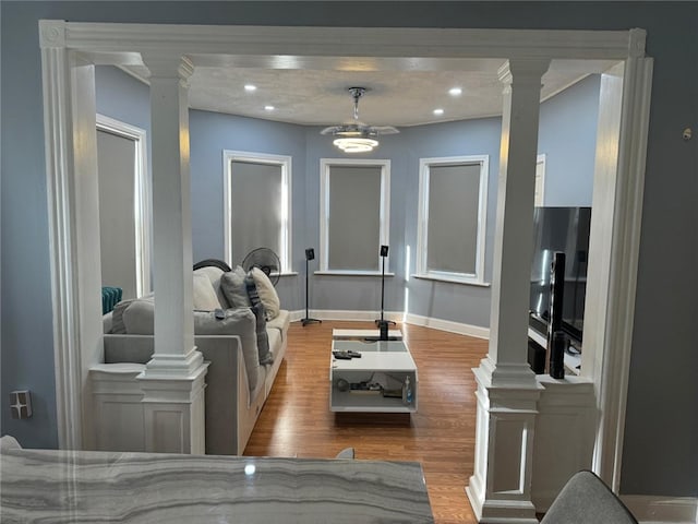 living room featuring ceiling fan, light wood-type flooring, and ornate columns