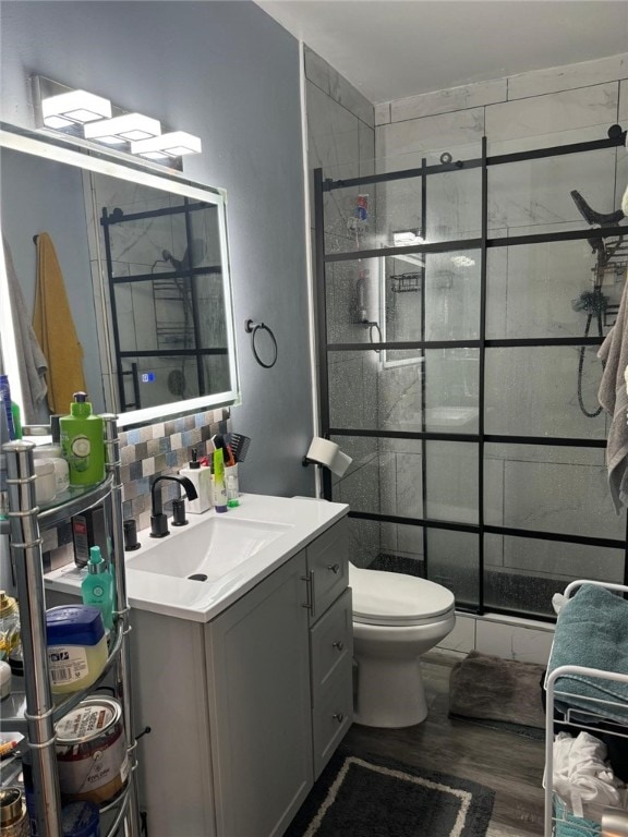 bathroom featuring vanity, toilet, walk in shower, tasteful backsplash, and wood-type flooring