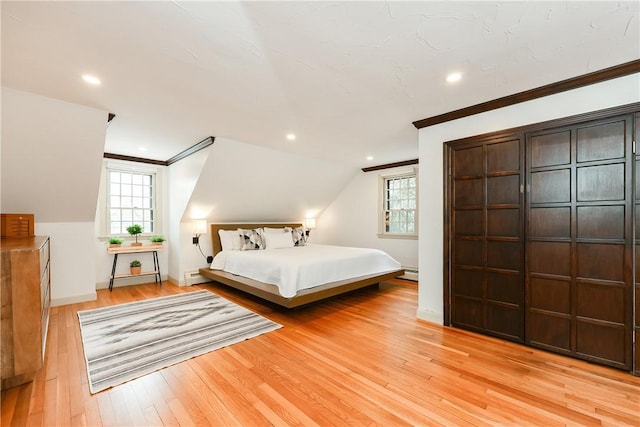 bedroom with lofted ceiling, a baseboard heating unit, ornamental molding, and light hardwood / wood-style flooring