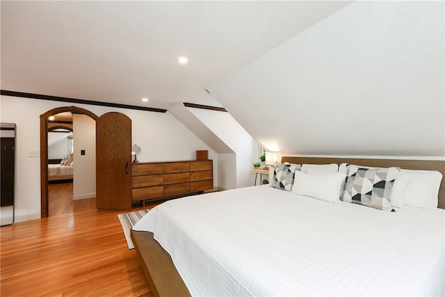 bedroom with lofted ceiling, light wood-type flooring, and ornamental molding