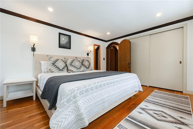 bedroom featuring a closet, crown molding, and hardwood / wood-style flooring