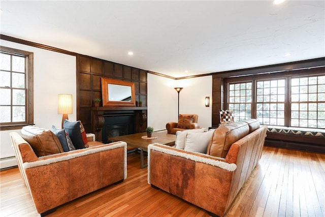 living room featuring a large fireplace, light hardwood / wood-style flooring, and crown molding