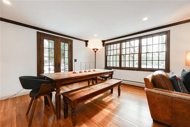 dining space featuring light wood-type flooring, baseboard heating, crown molding, and french doors