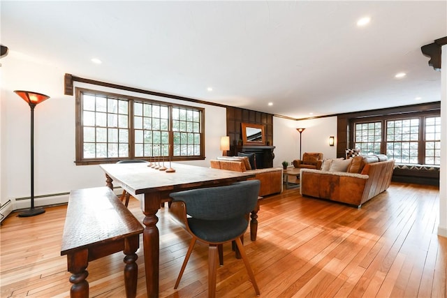 dining room with light wood-type flooring, crown molding, and a baseboard radiator