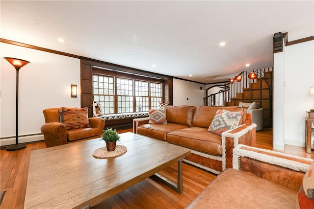 living room featuring light wood-type flooring, baseboard heating, and crown molding