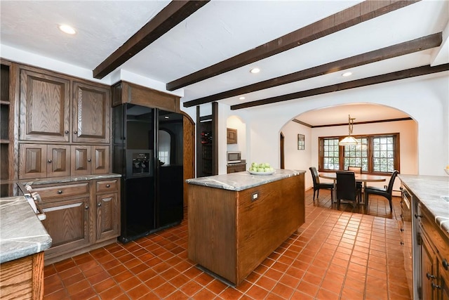 kitchen with dark tile patterned floors, light stone counters, stainless steel appliances, and a kitchen island