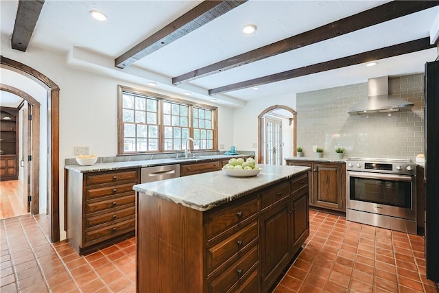 kitchen featuring backsplash, a center island, sink, appliances with stainless steel finishes, and wall chimney exhaust hood