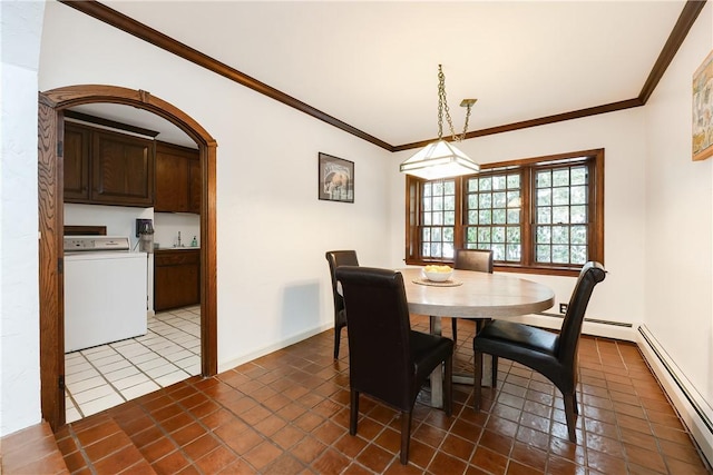 dining space featuring dark tile patterned floors, crown molding, washer / dryer, and a baseboard radiator