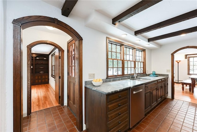 kitchen featuring dark brown cabinetry, dark tile patterned floors, sink, light stone counters, and stainless steel dishwasher