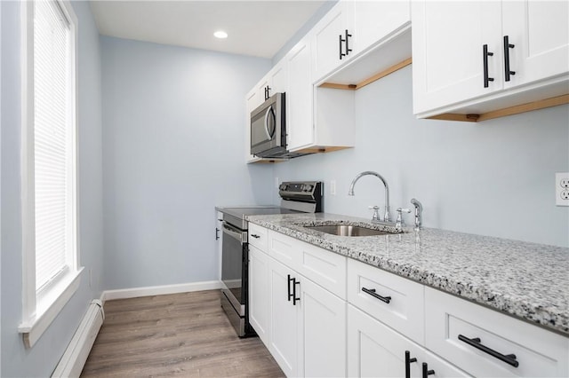 kitchen featuring sink, light stone counters, stainless steel range with electric stovetop, white cabinets, and light wood-type flooring