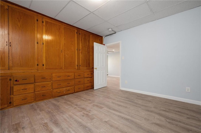 unfurnished bedroom with light wood-type flooring and a paneled ceiling