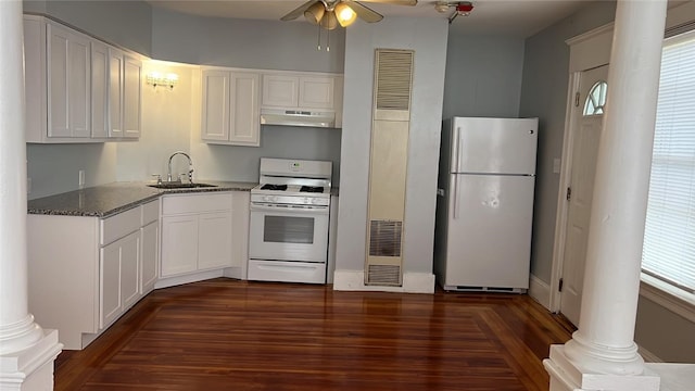 kitchen with a wealth of natural light, dark stone counters, white appliances, sink, and white cabinets