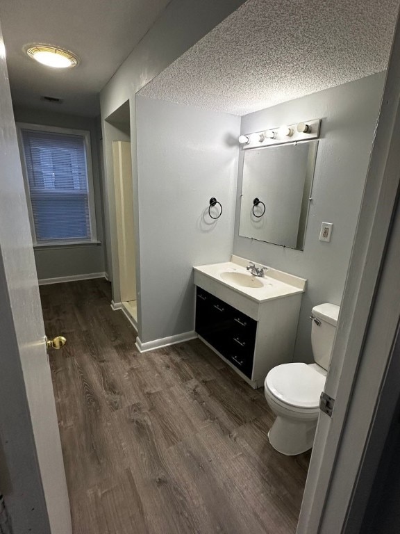 bathroom with a shower, a textured ceiling, toilet, vanity, and hardwood / wood-style flooring