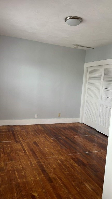 unfurnished bedroom featuring dark hardwood / wood-style flooring and a closet