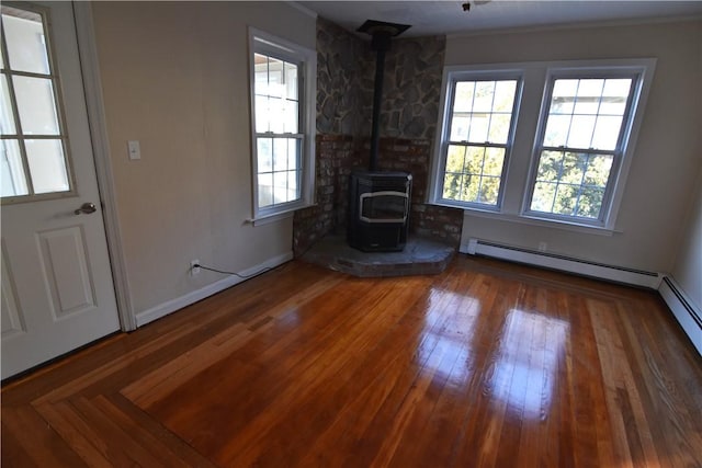 unfurnished living room with a wood stove, a wealth of natural light, and wood-type flooring