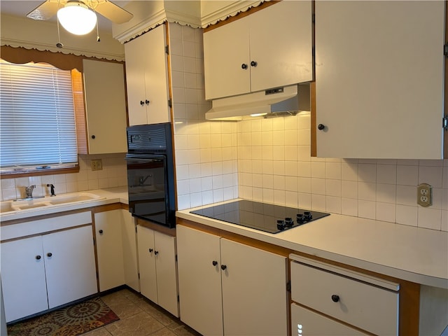 kitchen featuring decorative backsplash, sink, black appliances, dark tile patterned flooring, and white cabinetry