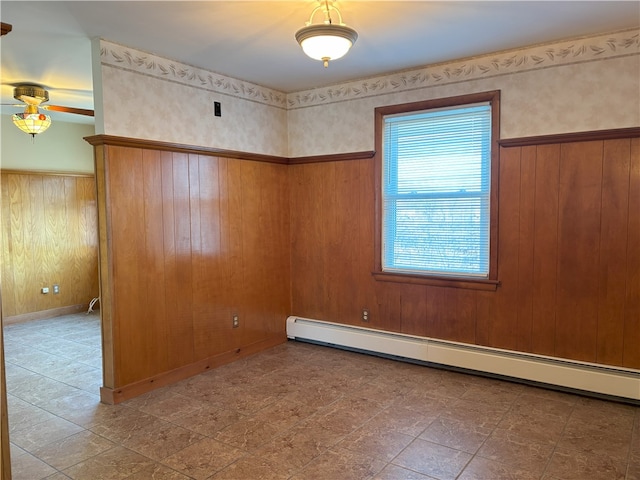 unfurnished room featuring baseboard heating, wooden walls, and ceiling fan