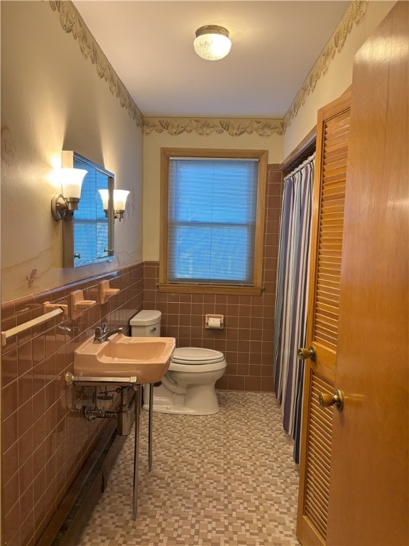 bathroom with toilet, tile walls, and sink