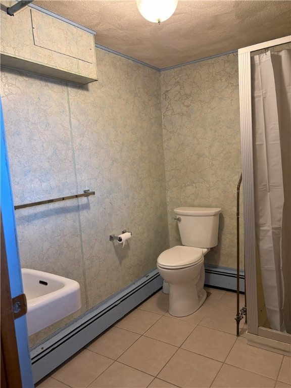 bathroom featuring tile patterned floors, a baseboard radiator, a textured ceiling, and toilet