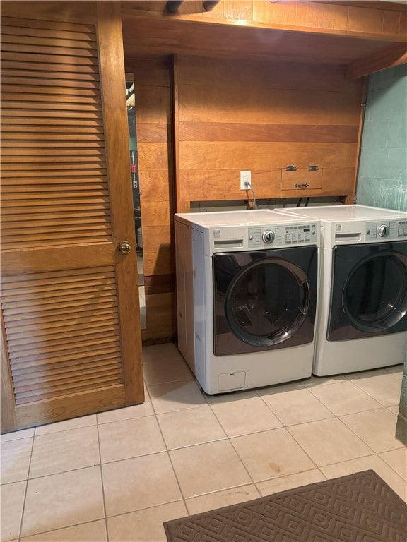 laundry area with wooden walls, independent washer and dryer, and light tile patterned floors