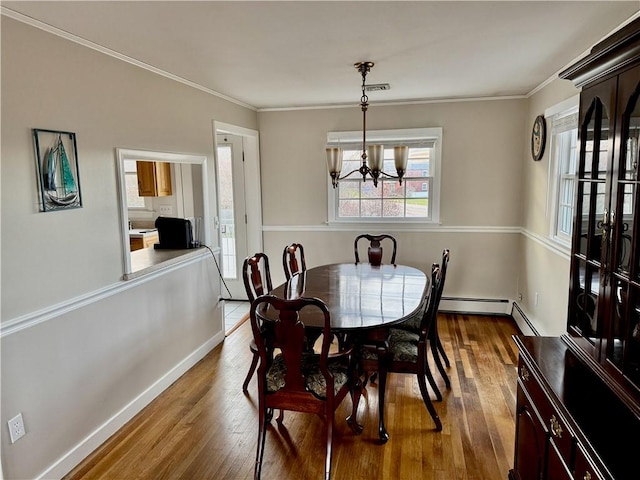 dining area featuring hardwood / wood-style floors, ornamental molding, and an inviting chandelier