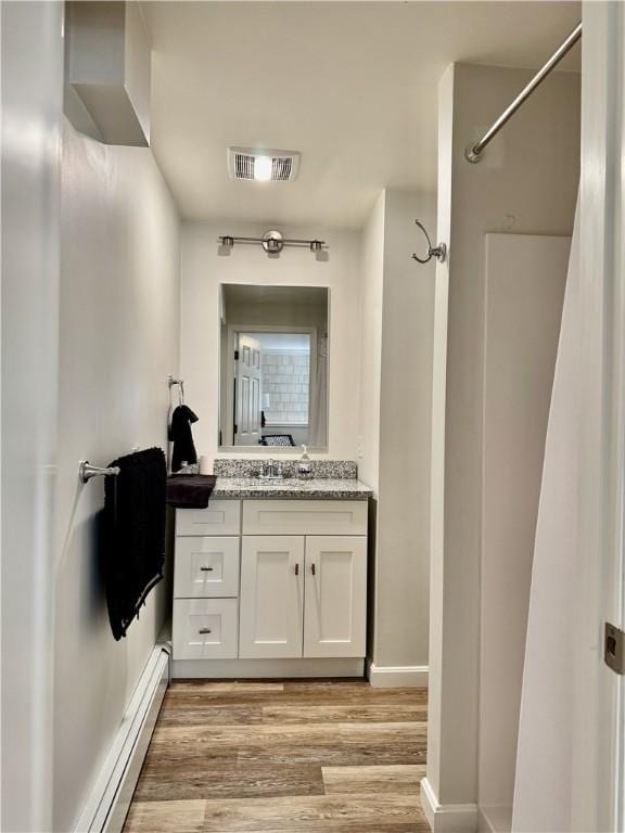 bathroom featuring wood-type flooring, a baseboard radiator, a shower, and vanity