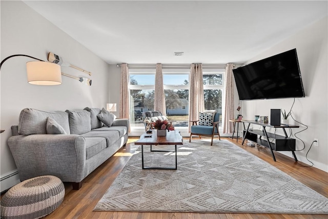 living area featuring a baseboard heating unit, visible vents, and wood finished floors