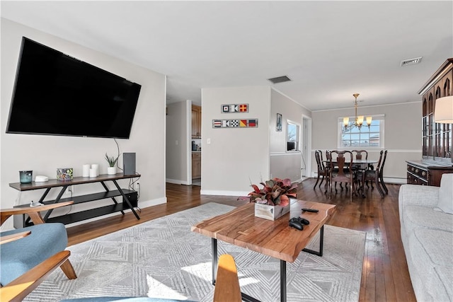 living area featuring visible vents, a notable chandelier, baseboards, and hardwood / wood-style flooring