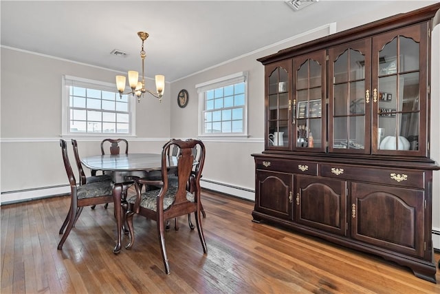 dining area featuring hardwood / wood-style floors, baseboard heating, visible vents, and crown molding