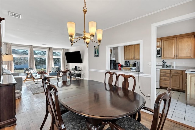 dining space with a chandelier, visible vents, crown molding, and light wood-style flooring