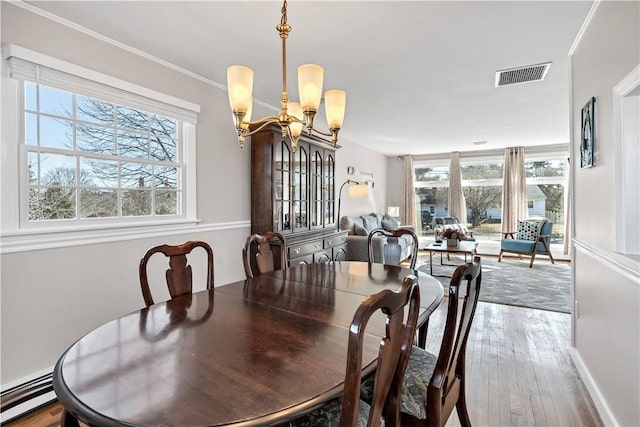 dining area with hardwood / wood-style flooring, a baseboard radiator, visible vents, and an inviting chandelier