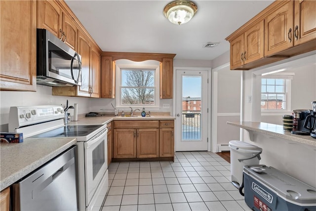 kitchen with stainless steel appliances, a sink, and light countertops