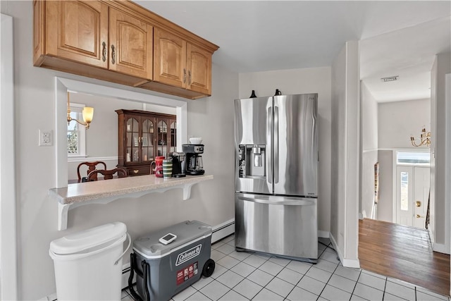 kitchen featuring visible vents, stainless steel fridge with ice dispenser, light countertops, a baseboard heating unit, and light tile patterned flooring