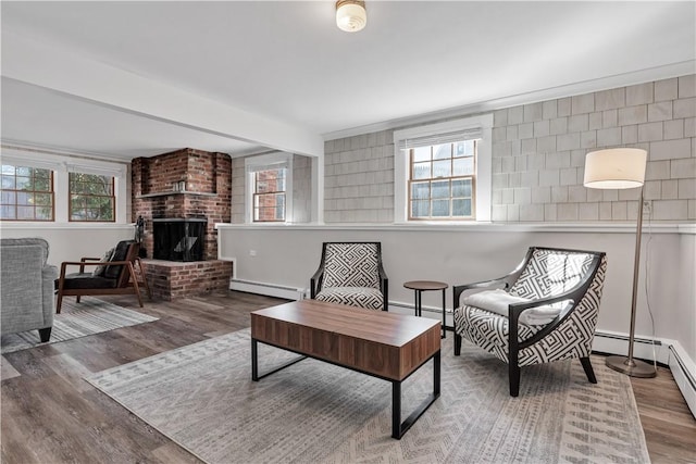 living area featuring a healthy amount of sunlight, a brick fireplace, and a baseboard heating unit