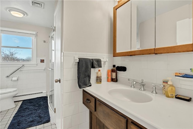 bathroom featuring visible vents, toilet, baseboard heating, vanity, and tile walls