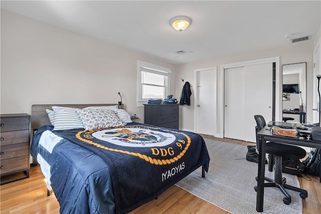 bedroom with a closet, visible vents, and wood finished floors