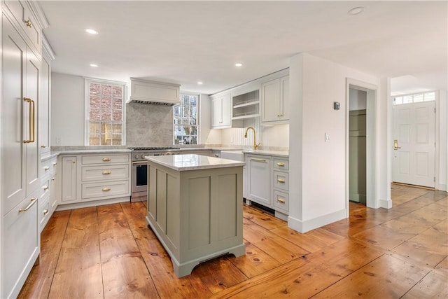 kitchen featuring refrigerator, tasteful backsplash, high end stainless steel range oven, light hardwood / wood-style flooring, and a center island