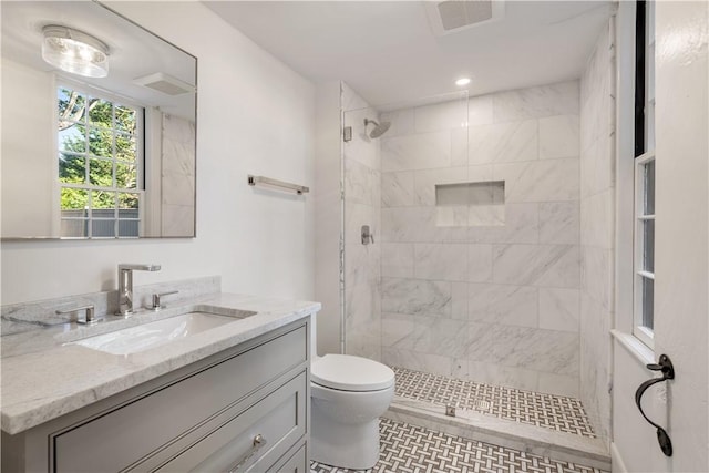 bathroom with a tile shower, vanity, and toilet