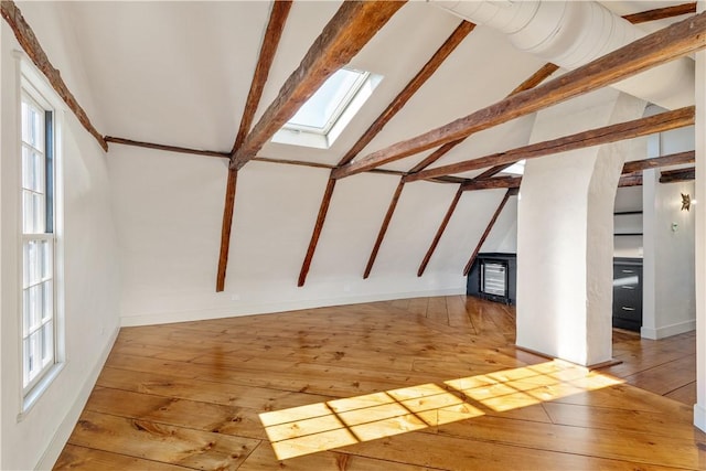 bonus room featuring beam ceiling, a skylight, and wood-type flooring