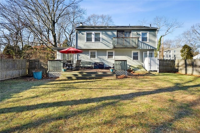 rear view of house featuring a yard, a balcony, and a deck