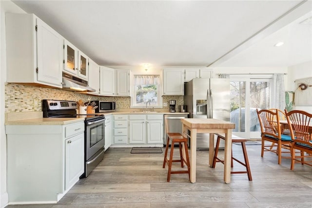 kitchen with appliances with stainless steel finishes, light wood-type flooring, backsplash, sink, and white cabinets