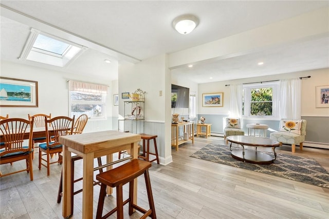 dining area with light hardwood / wood-style floors and a skylight