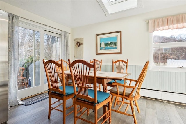 dining room with a skylight, a healthy amount of sunlight, and wood-type flooring